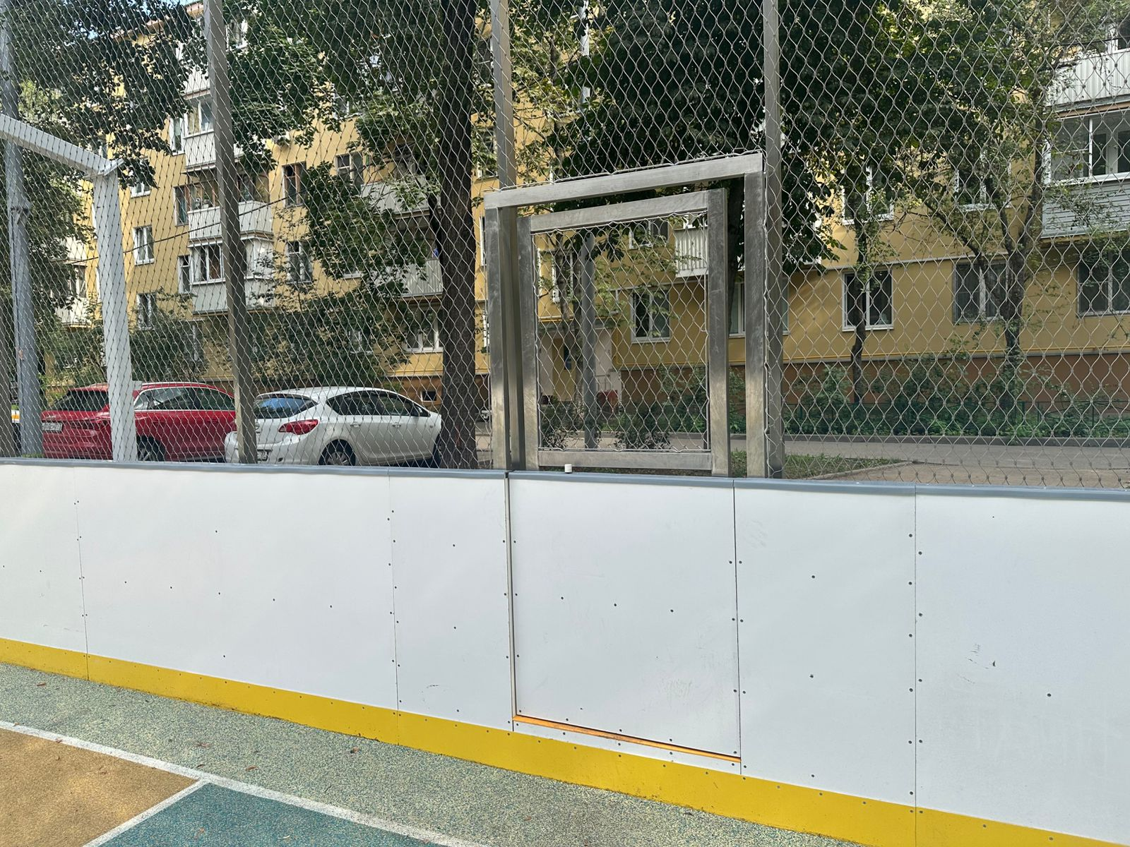 Side view stainless cable mesh fence around community sport court with residential building background