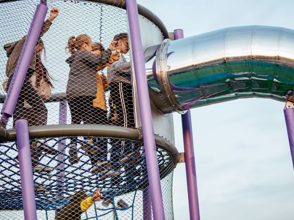 Close-up kids climbing through transparent stainless mesh on circular deck