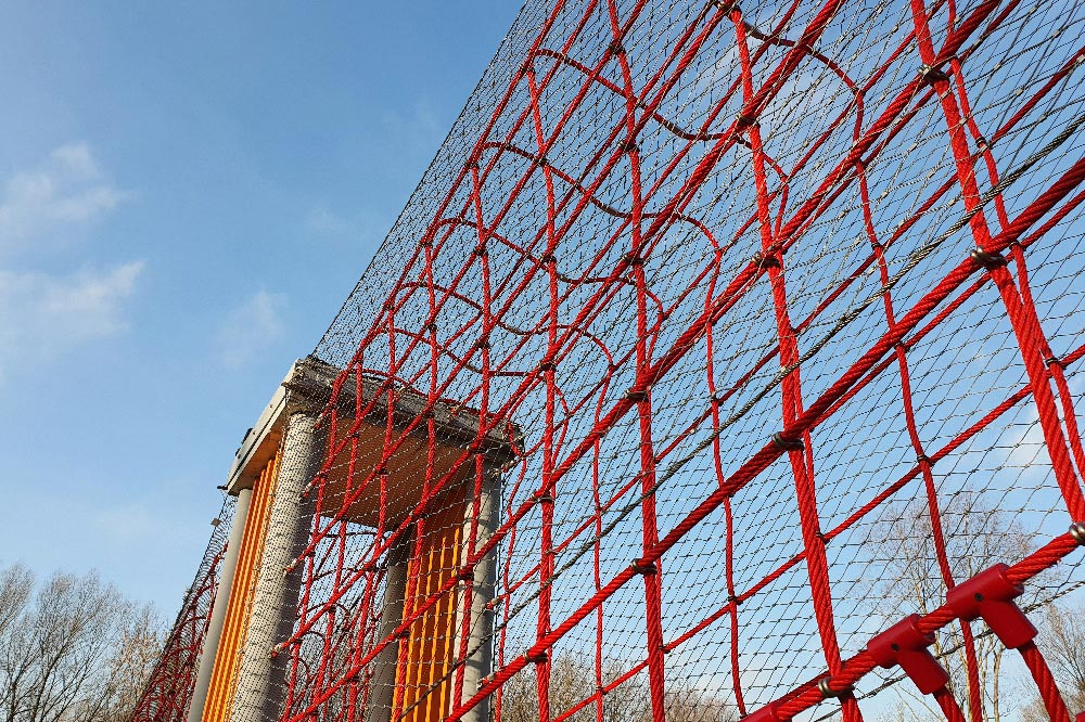 Low angle shot red suspended cable mesh bridge sky background