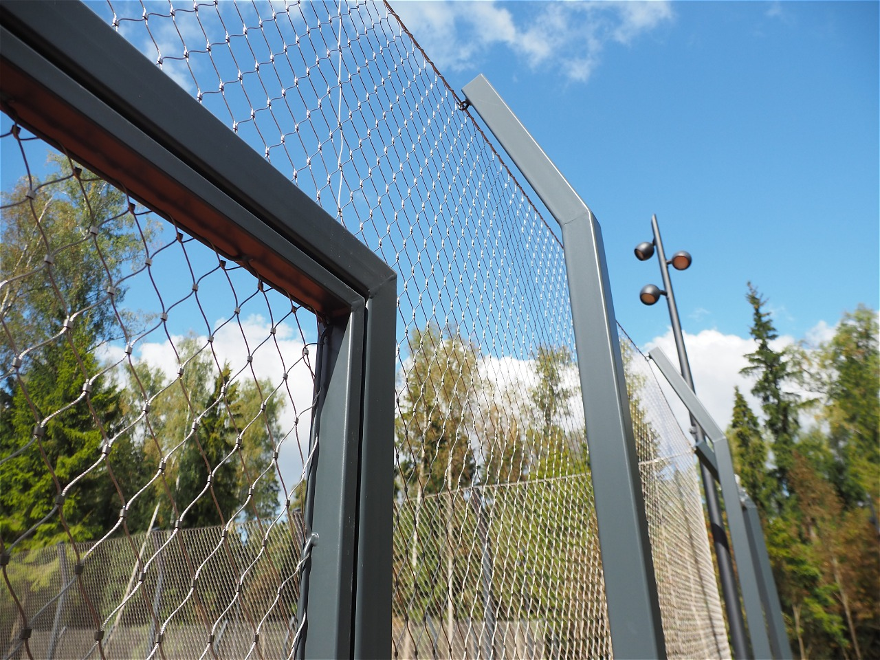 Close-up shot angular black coated steel post top with stainless cable mesh connection detail